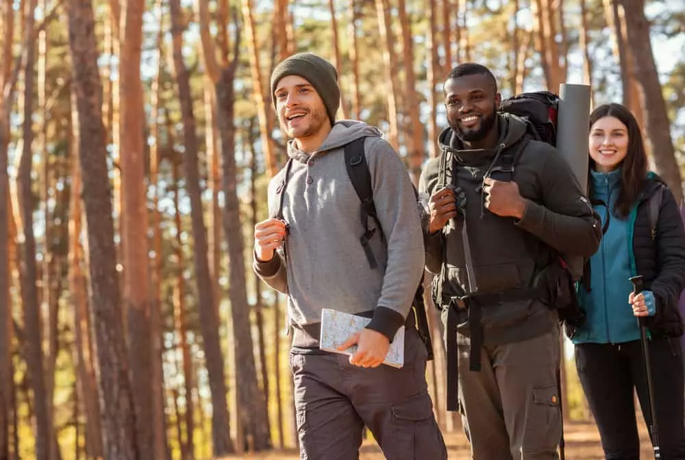 Three,Cheerful,Multiracial,Friends,Hiking,By,Forest,,Going,Towards,Free