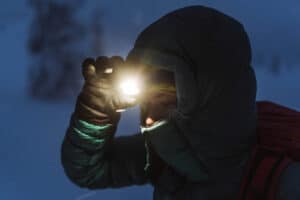 woman turning on headlamp as it gets dark during a winter hike