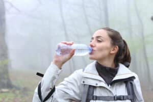 young woman drinking water on hiking trail