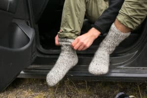man putting on wool socks before going on a winter hike